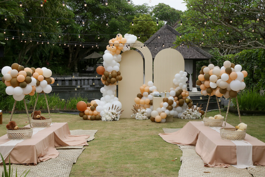 Elegant outdoor baby shower setup with balloon arches and seating
